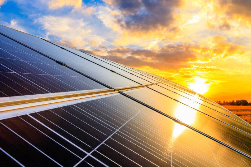 Solar panels on warehouse roof with the sun in the background