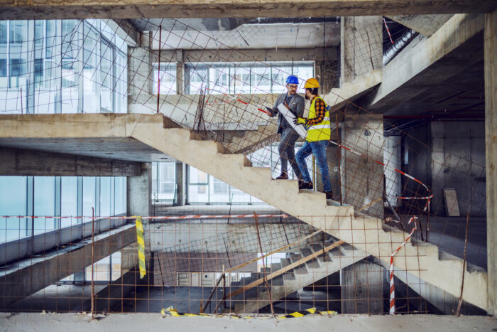 Construction worker and main architect climbing stairs at construction site